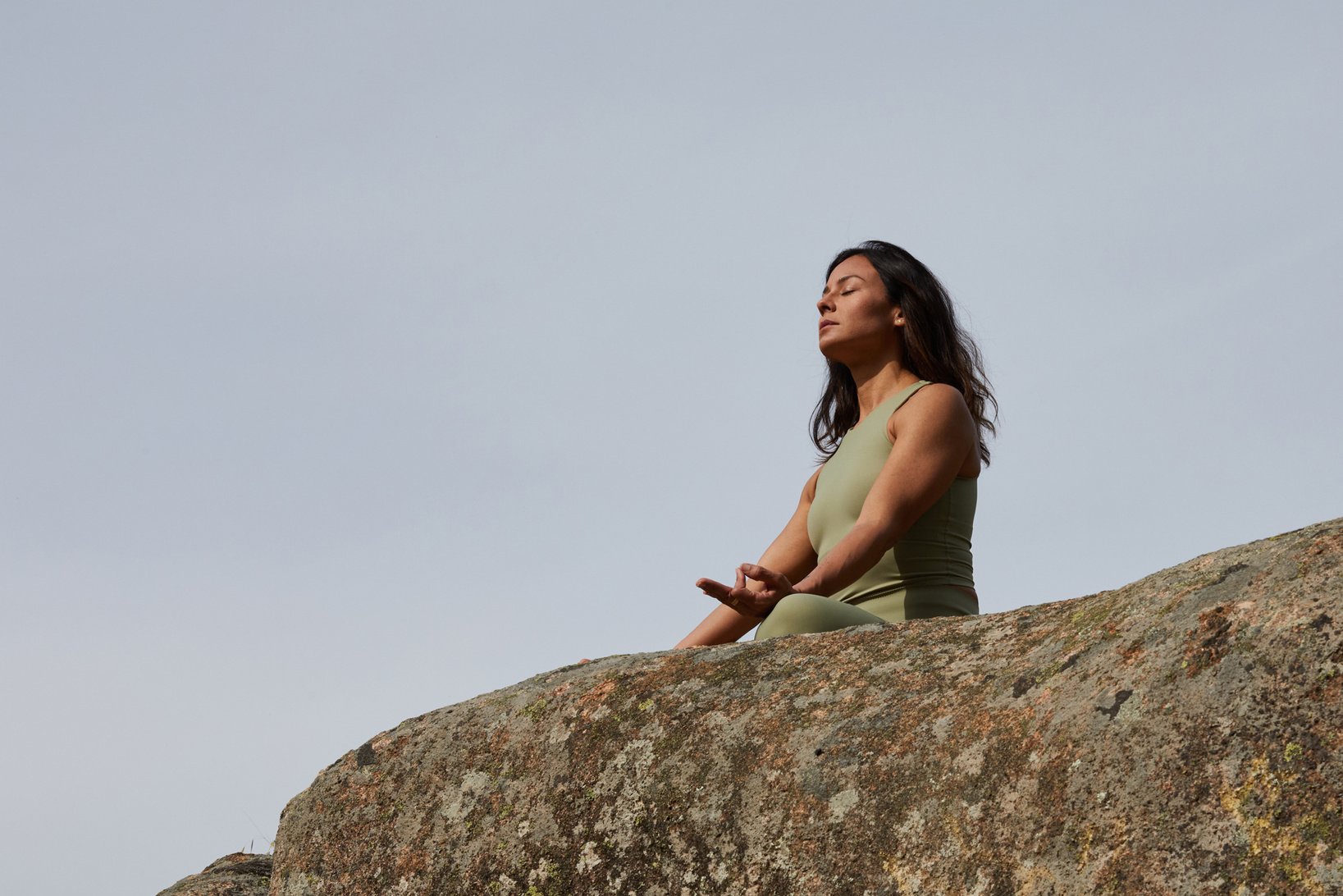 Woman Meditating on Top of a Rock